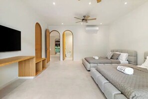 Quarto moderno com uma cama grande, TV na parede e ventoinha de teto.