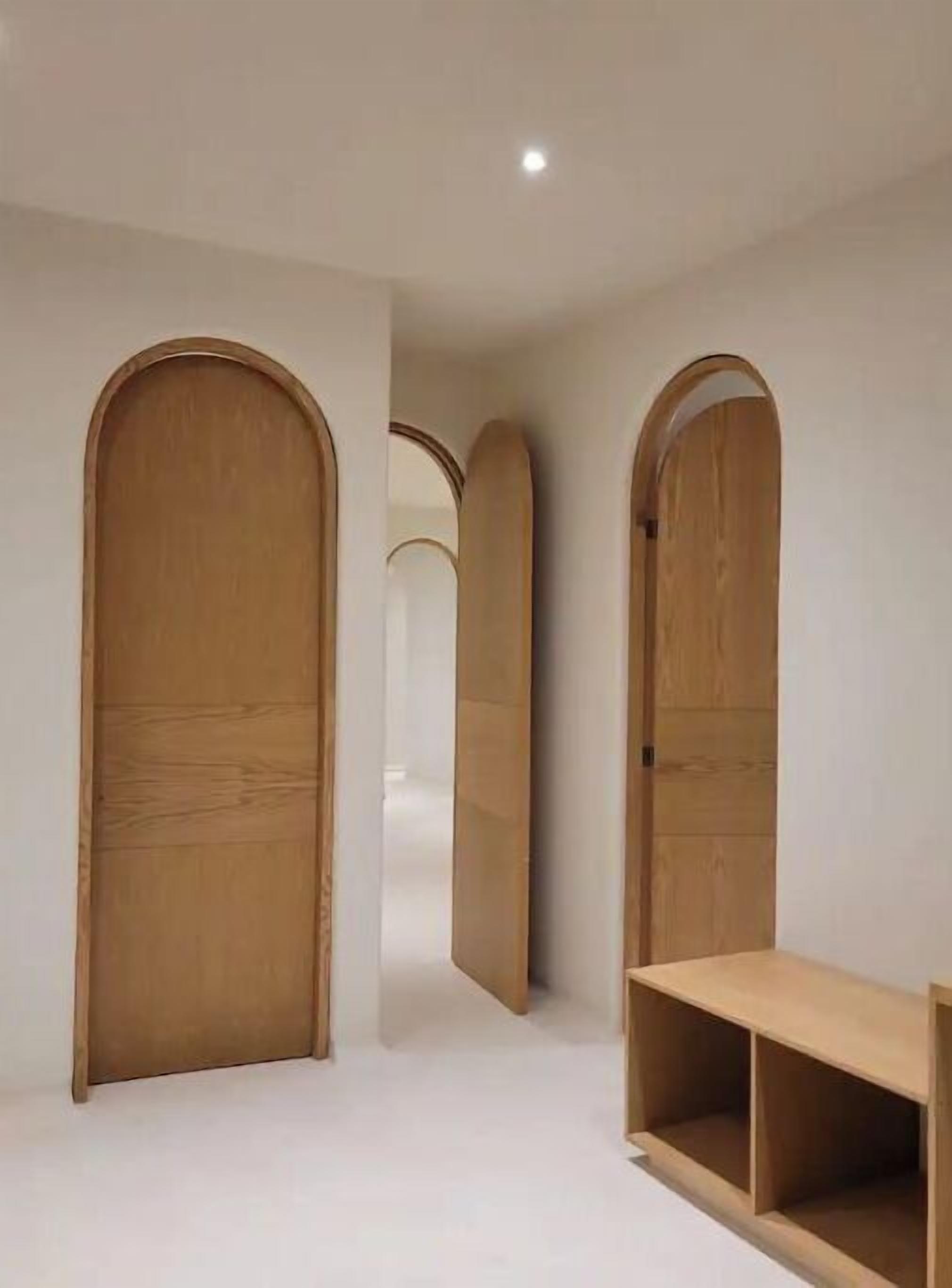 Un couloir avec des portes en bois et un banc en bois.
