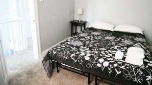 A bedroom with a bed, a nightstand, and a door to a balcony. - Clover2900 Apartment & Rooms in S Philly (Philadelphia)