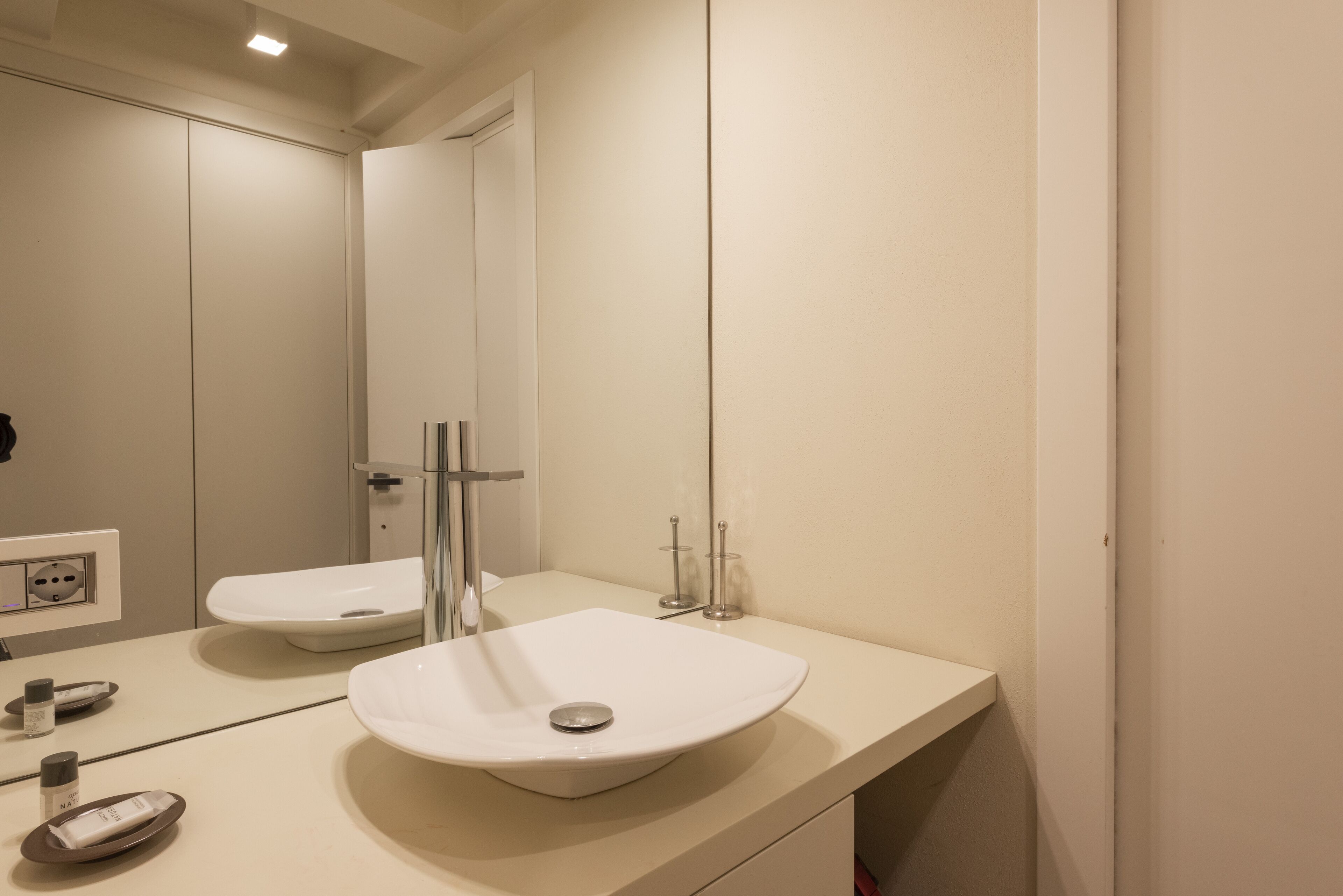 A modern bathroom with a white sink, mirror, and a toilet.