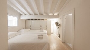 A hotel room with two beds, a TV, and a wardrobe. - Le Grazie Luxury Apartment by Mmega (Florence)