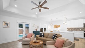 A spacious living room with a large sofa, a coffee table, and a ceiling fan. - Beach House - The Sanderling by PHG (Panama City Beach)