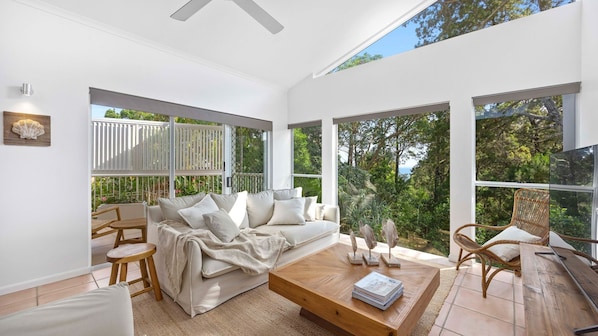Relax in this serene space with a comfortable sofa set and expansive views of lush greenery.