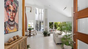 A spacious living area with a dining table, a sofa, and a large window offering a view of the outdoors.