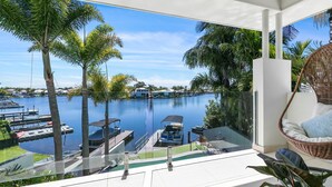 A balcony with a view of a marina, palm trees, and a clear sky.
