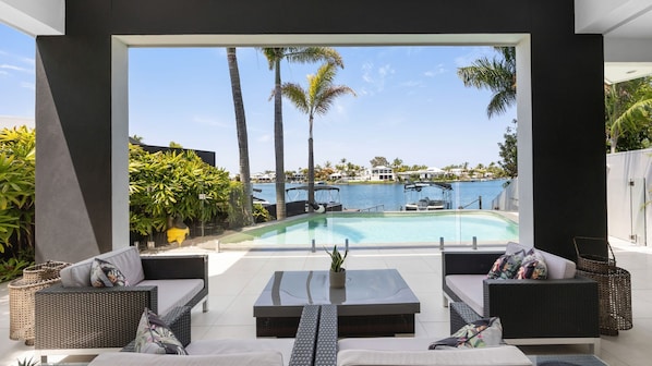 Relax in style with a clear view of the pool and marina from this outdoor living space, featuring comfortable seating and a central table.