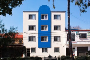 Un immeuble à plusieurs étages, caractérisé par une bande verticale bleue distinctive et de nombreuses fenêtres.