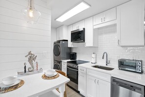 A modern kitchen with white cabinetry, a built-in microwave, a toaster, and a dishwasher. - 30A Emerald Hill by Panhandle Getaways (Santa Rosa Beach)