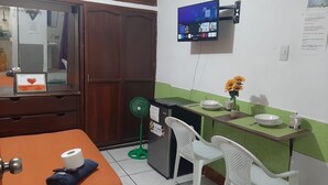 Een kamer met een bed, een bureau met een computerscherm, een groene wand en een raam.