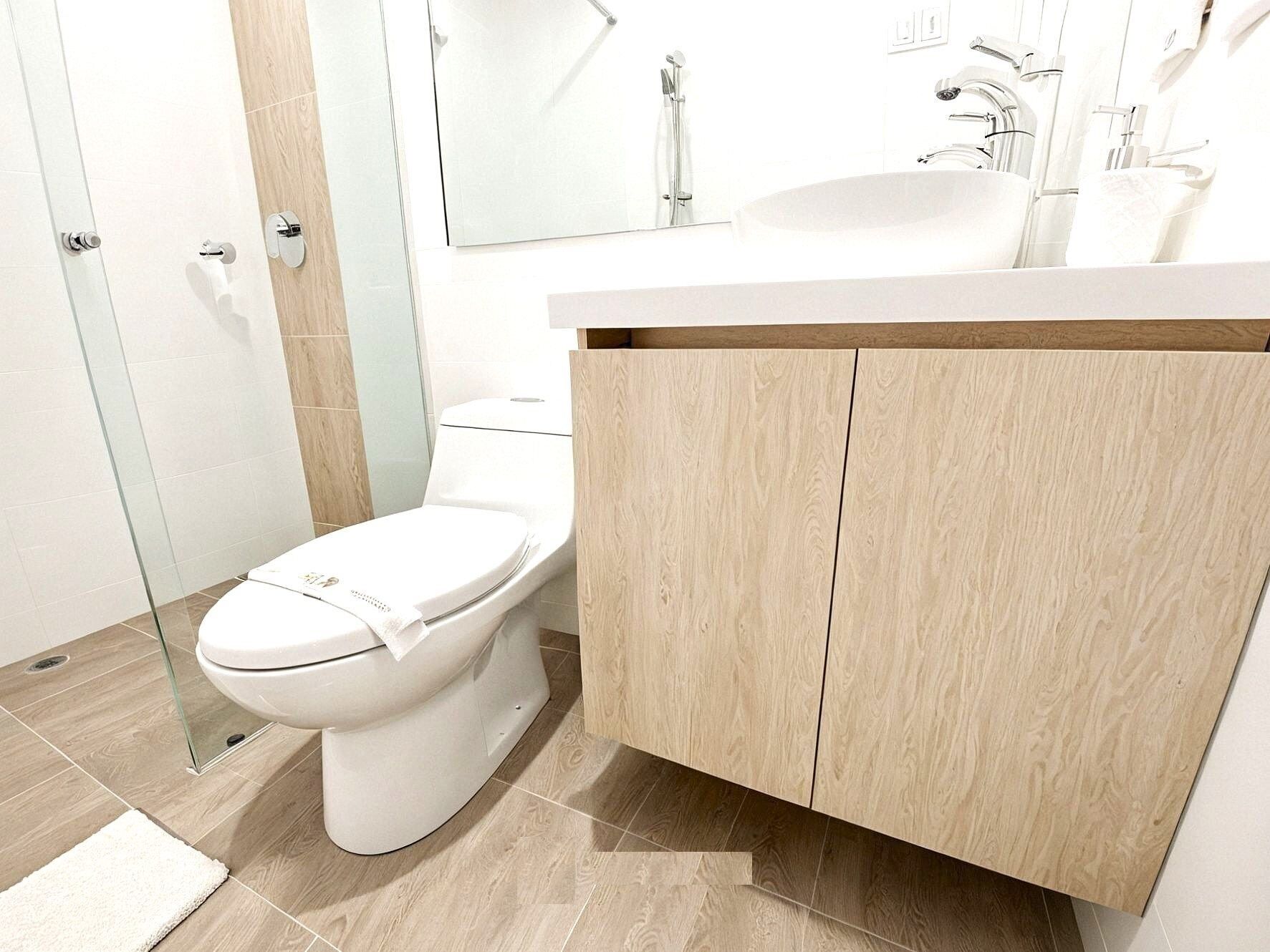 A modern bathroom with a toilet, a sink, and a mirror.