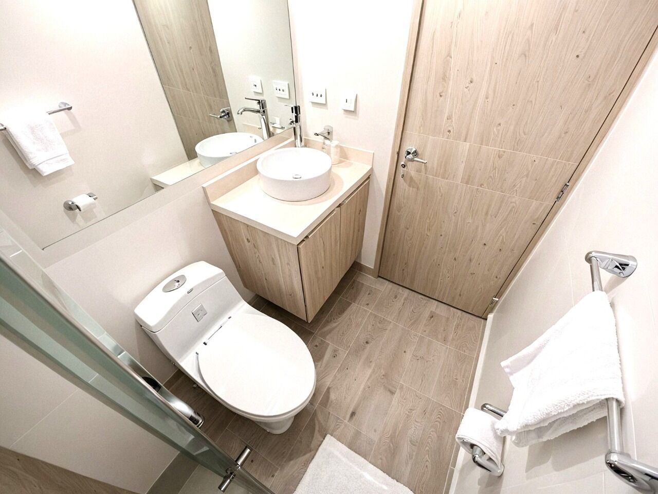 A modern bathroom with a toilet, sink, and mirror.