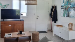 Ein modernes Wohnzimmer mit einer Couch, einem Couchtisch, einem Fernseher und einer Pendelleuchte.