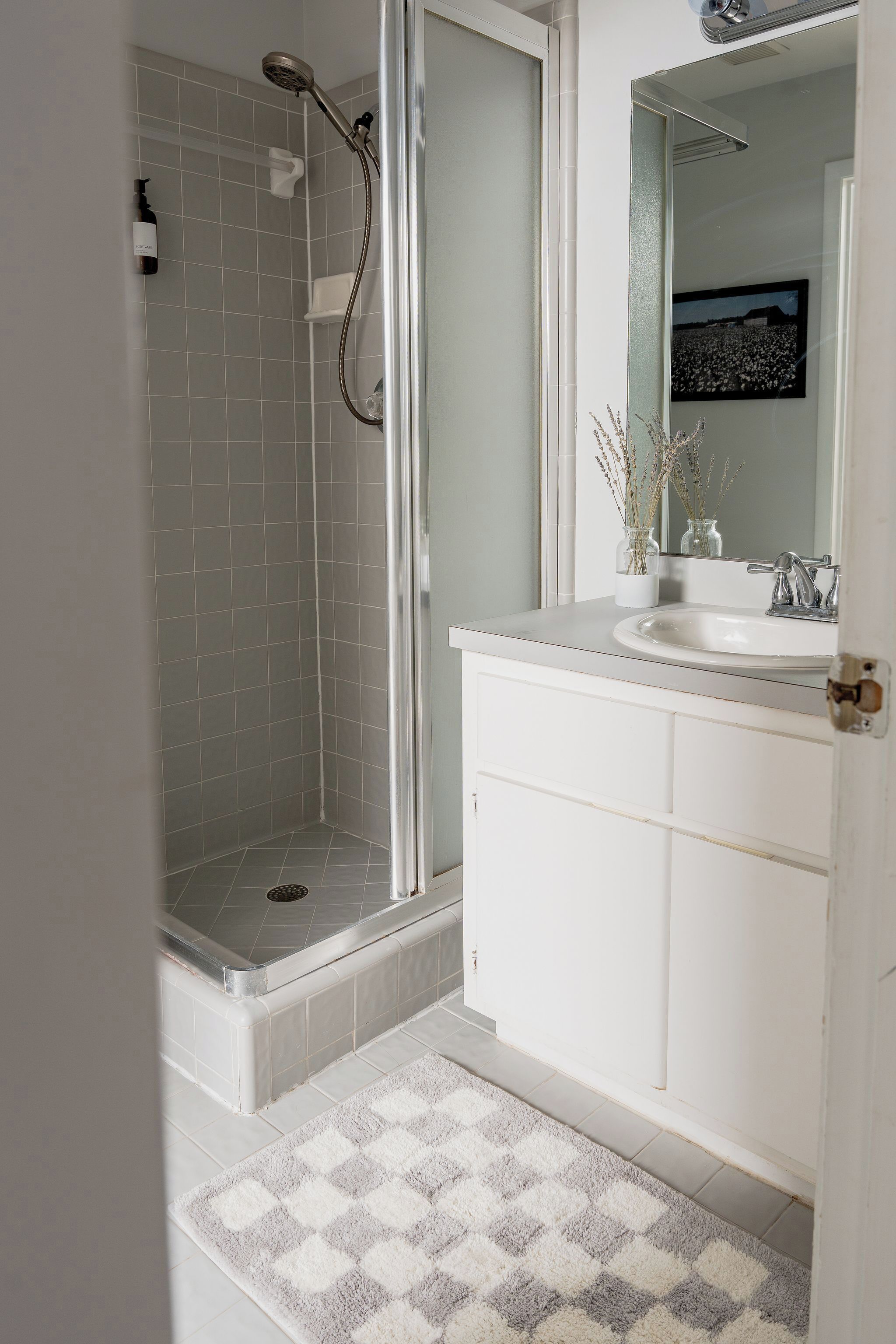 A bathroom with a shower, a sink, and a mirror.