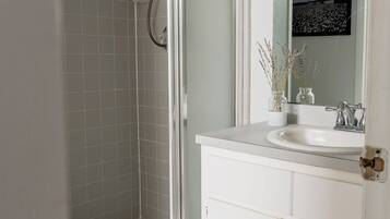 A bathroom with a shower, a sink, and a mirror.