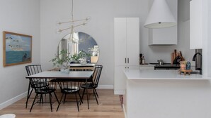 A modern kitchen with white cabinets, a central island, and a hanging light fixture. - Quiet, convenient & Modern Haven (Gainesville)