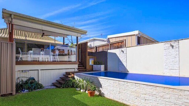 Una casa moderna amb piscina, un porxo cobert i un jardí ben cuidat.