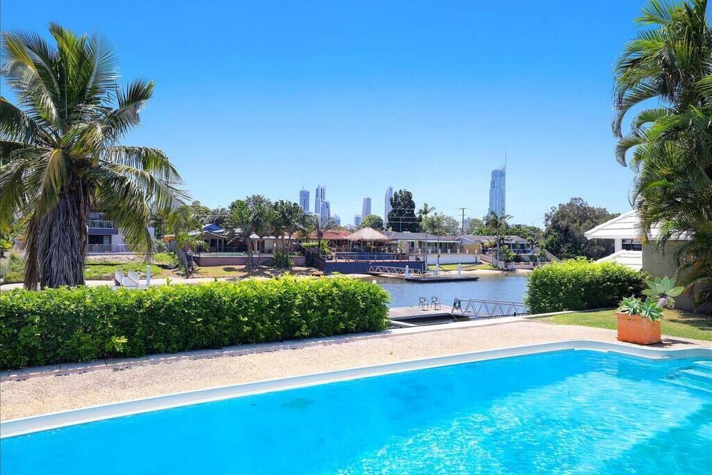 Una piscina con vista sullo skyline cittadino, palme e un elemento d'acqua.