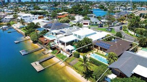 An aerial view of a coastal residential area with houses, a marina, and a city skyline in the background. - Waterfront Capri -Walk to cafes by Bnbbooking (Surfers Paradise)