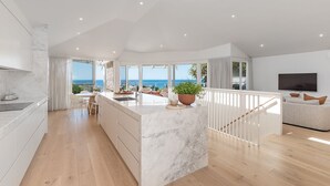 Una cocina moderna con una isla de mármol, ventanas amplias y vistas al mar.