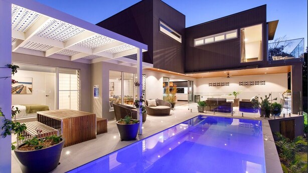 A modern house with a swimming pool, outdoor seating, and a covered patio area.