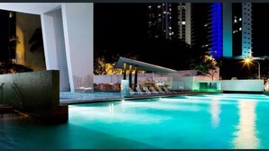 Un espace piscine doté d’une architecture moderne, comprenant un espace salon couvert et un coin détente au bord de la piscine.