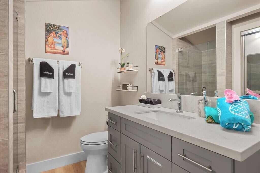A bathroom with a toilet, a sink, a mirror, and towels.