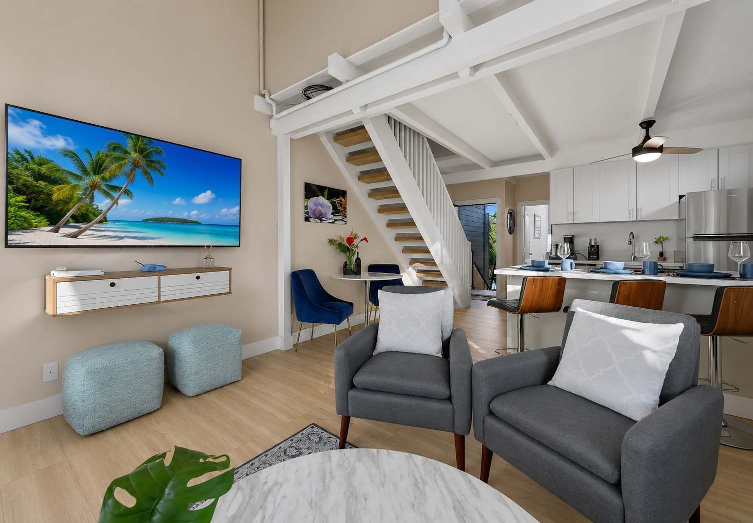 A modern living room with a TV, grey sofas, a dining area, and a kitchen.