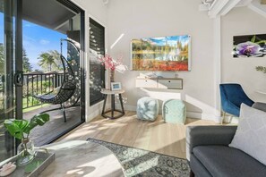 A modern living room with a sofa, a chair, a small table, and a painting on the wall.