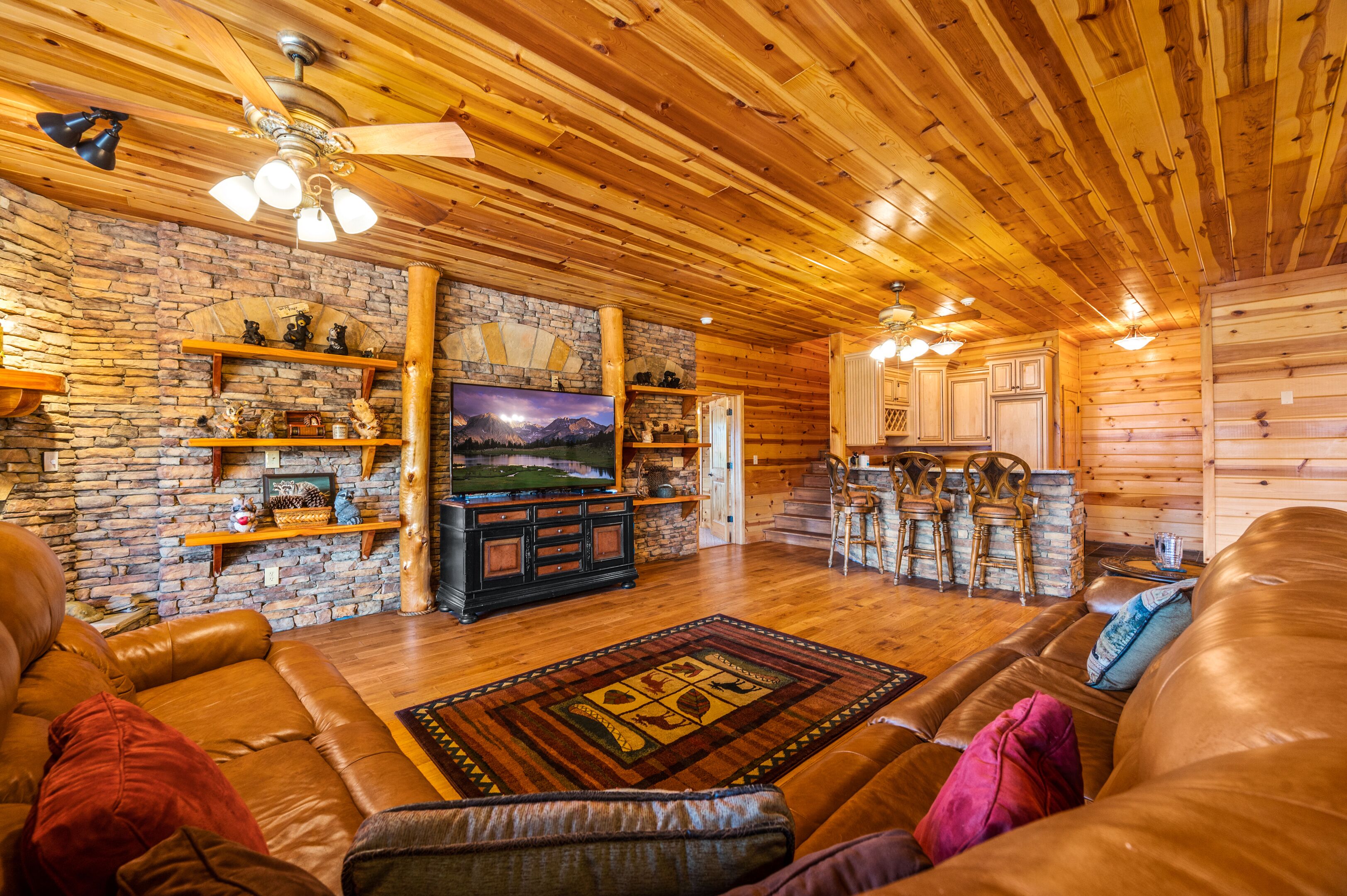 Ein gemütliches Blockhaus-Interieur mit Steinwand, Holzbalkendecke, Ledersofa und Kamin.