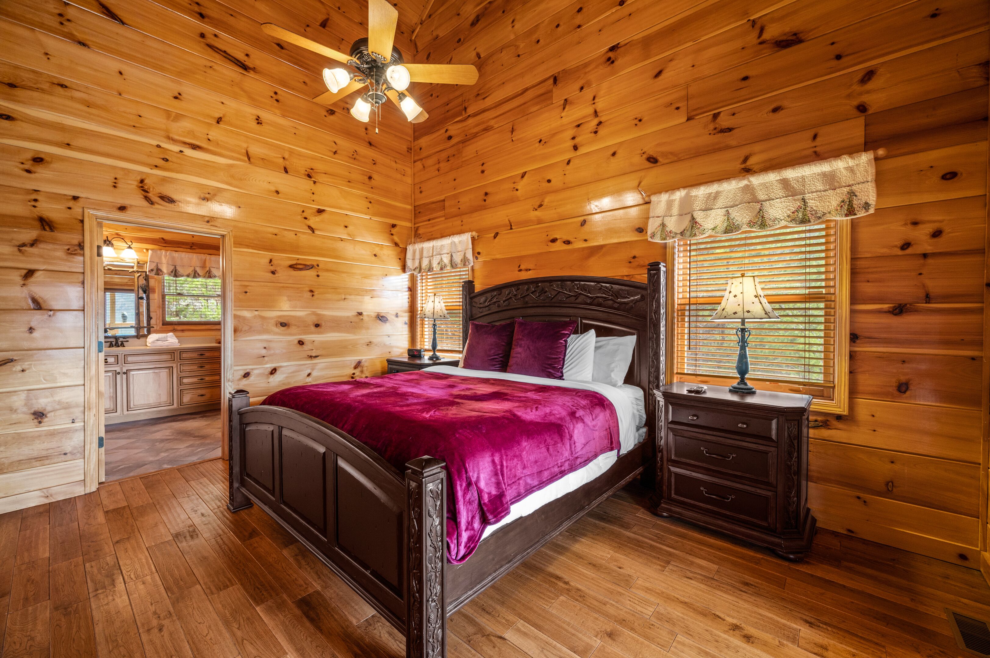A wooden cabin bedroom with a bed, nightstands, and a ceiling fan.
