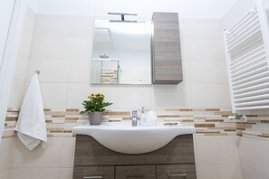 Familie driepersoonskamer | Badkamer | Een douche, een regendouche, een haardroger, een bidet