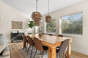 Un espace repas avec une table en bois, des chaises et des luminaires suspendus.