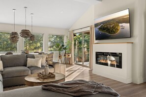 Una sala de estar moderna con chimenea, un sofá, una mesa de centro y un televisor montado en la pared.