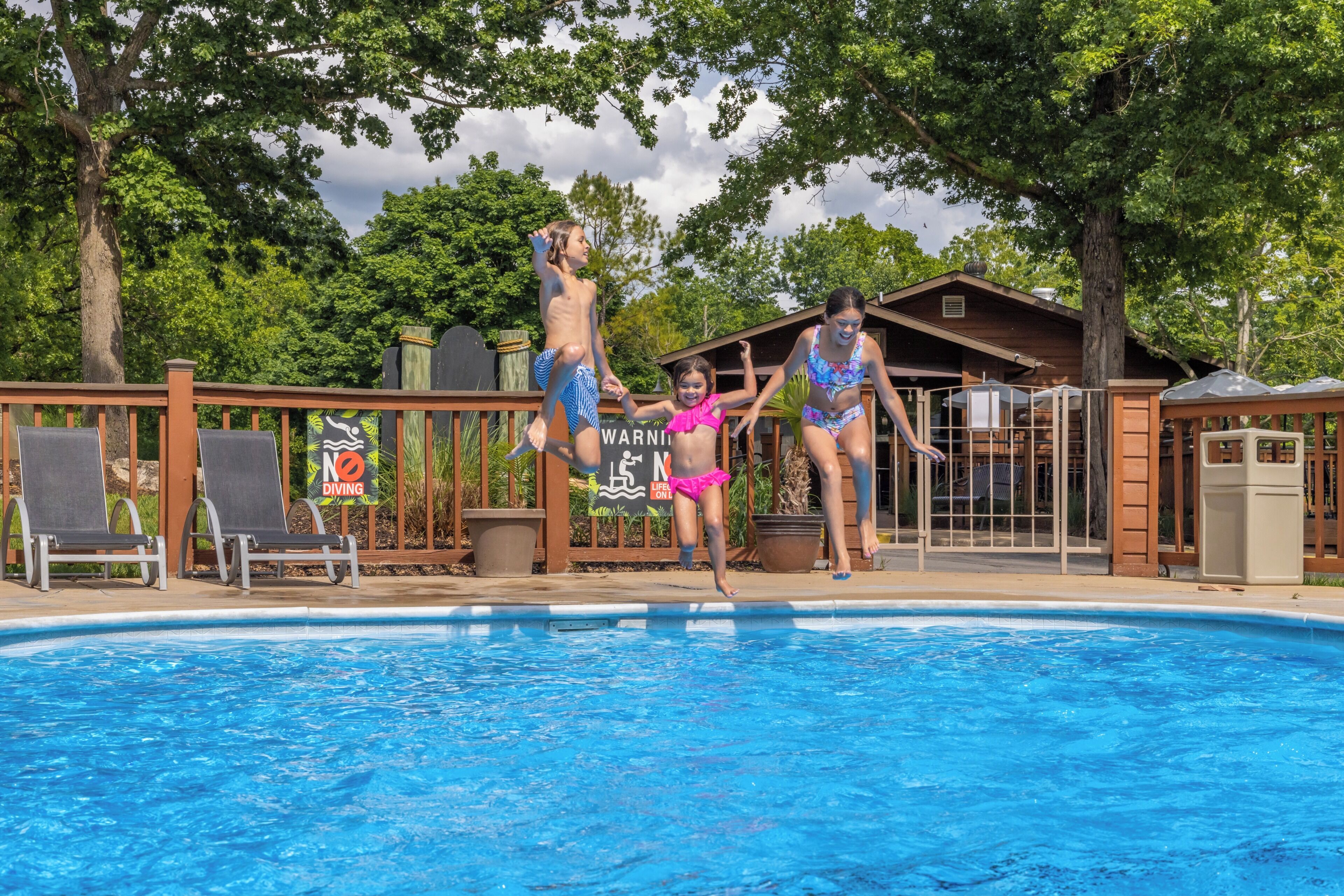 Une piscine avec une terrasse en bois, des chaises longues et un chalet en bois en arrière-plan.