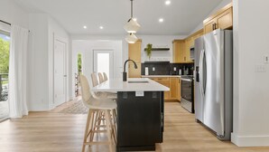 Una cocina moderna con una isla central, electrodomésticos de acero inoxidable y armarios de madera.