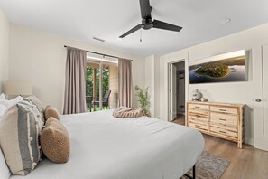 Une chambre à coucher avec un lit, un ventilateur de plafond, une télévision et une vue sur un lac.