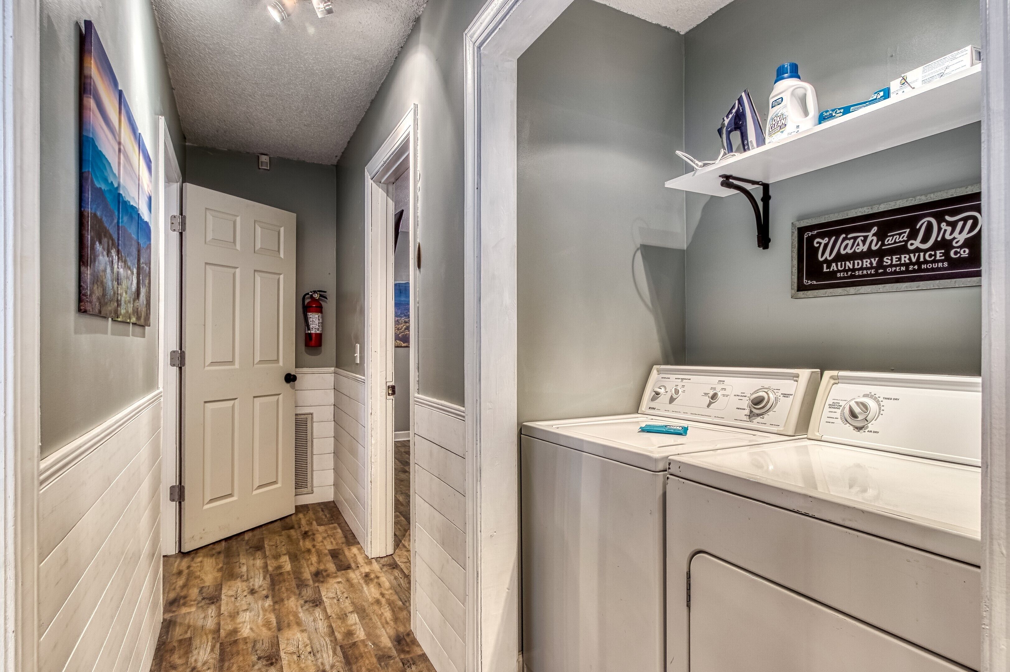 A laundry room with a sign for 'Wash and Dry Laundry Service Co.' and a fire extinguisher on the wall.