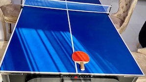 A ping pong table with two red paddles and a ball rack. - Harrington court (Lekki)