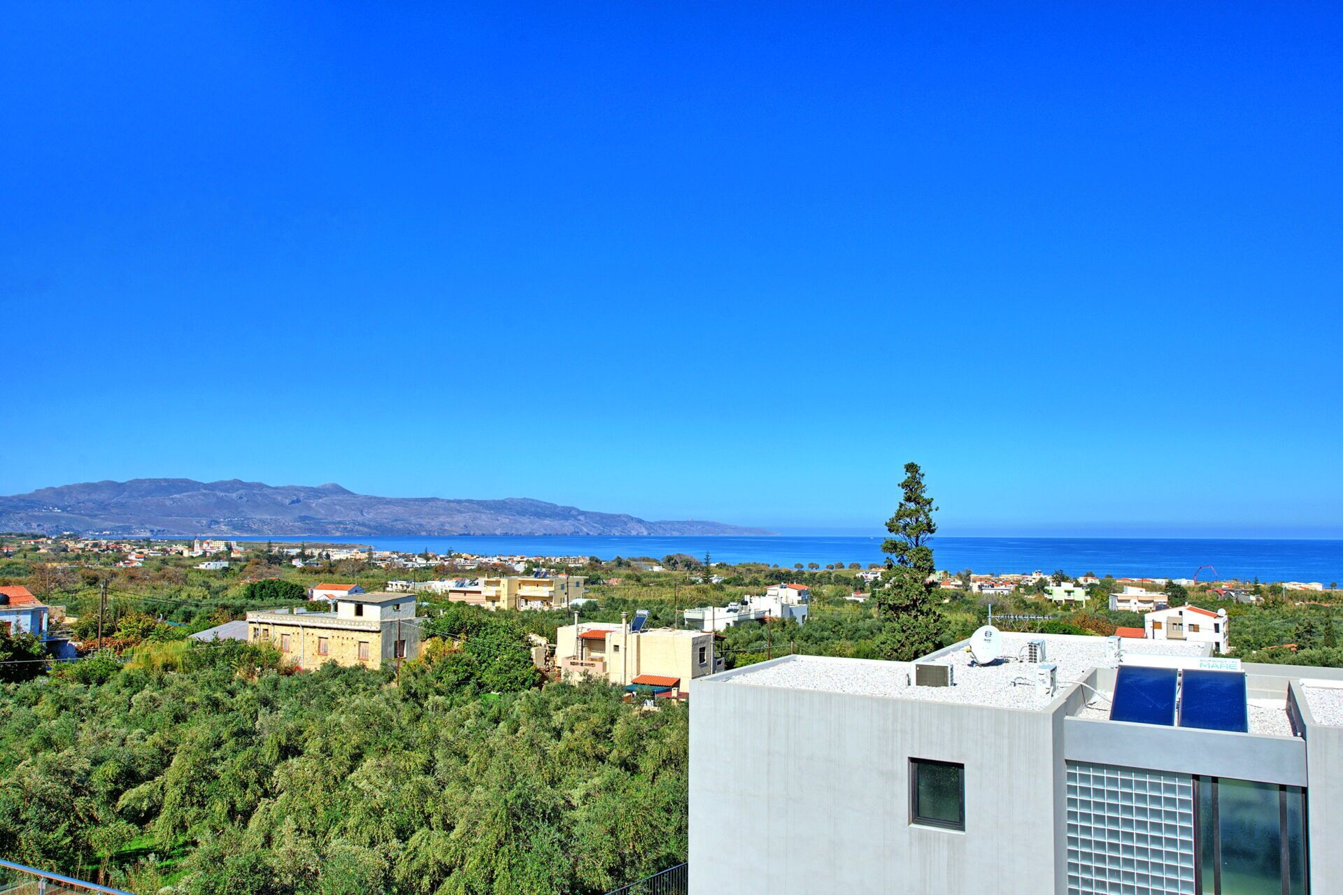 A coastal town with buildings, a clear blue sky, and a view of the sea.
