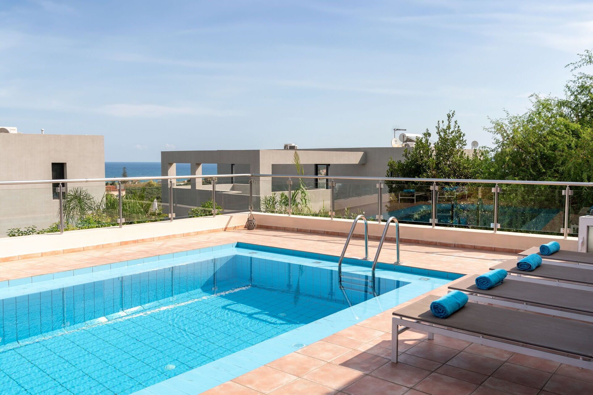Une piscine sur le toit, avec une eau d’un bleu cristallin, une balustrade en verre et une vue sur la mer.