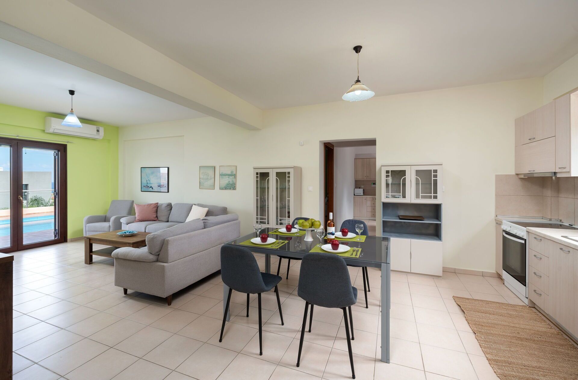 Un salon moderne comprenant un canapé, une table à manger et des chaises. On y trouve également un coin cuisine avec des placards et une cuisinière.