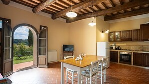 Une cuisine spacieuse avec une table et des chaises en bois, un téléviseur et des appareils électroménagers modernes.