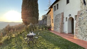 Un bâtiment en pierre doté d’un patio avec jardin, d’un grand arbre et d’un ciel dégagé.