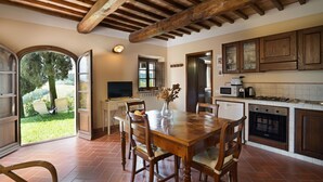 A spacious kitchen with wooden cabinets, a dining table with chairs, and a television. - Carro, Montauto - Holiday apartment  with pool close to San Gimignano (Montauto)