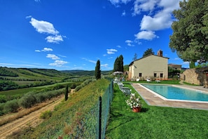Eine Villa mit Swimmingpool, umgeben von üppiger Vegetation und sanften Hügeln.