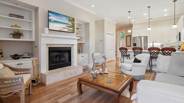 A living room with a fireplace, white sofas, a coffee table, and a dining area with chairs. - 10 Palm Villas Court (St Simons Island)