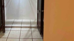 Quarto com soalho em mosaico, porta branca e interruptor de luz fixado na parede.