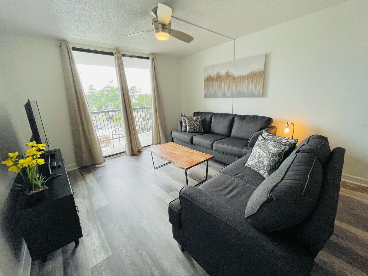 A modern living room with a grey sofa, a wooden coffee table, and a black TV stand.