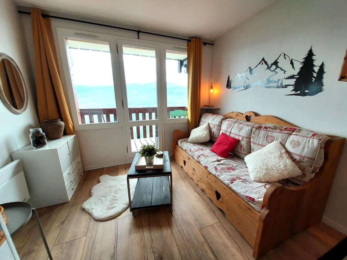 Una stanza accogliente con un divano in legno, un tavolino e vista mare da una porta finestra.
