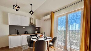 Een moderne keuken met witte kastjes, een eettafel gedekt voor twee personen, en een balkon met gordijnen.